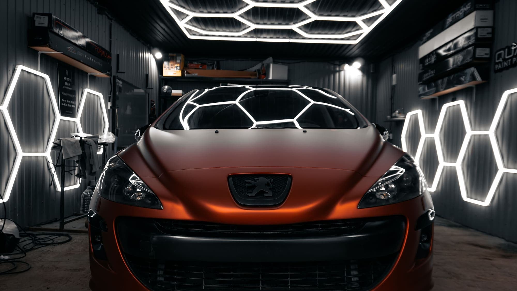 A car under hexagon lights in a detailing studio bay